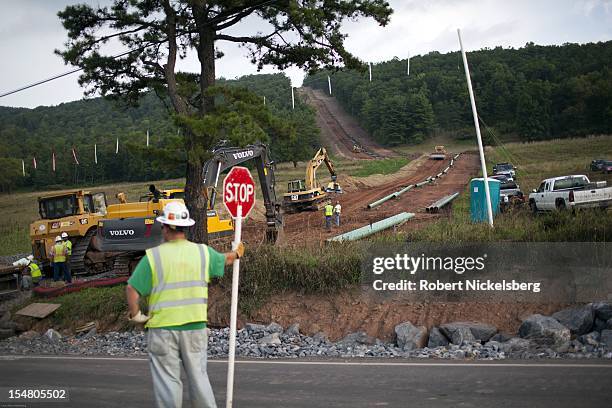 Construction worker directs traffic as work continues on a 10" water pipeline through wooded areas September 8, 2012 in Mifflin Township,...