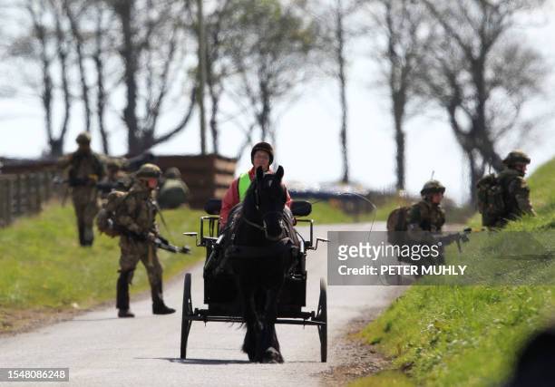 British soldiers cross a road behind a woman driving a horse and cart during the 16 Air Assault Brigade Exercise Joint Warrior at West Freugh...