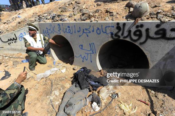 Libyan National Transitional Council fighter looks through a large concrete pipe where ousted Libyan leader Moamer Kadhafi was allegedly captured,...