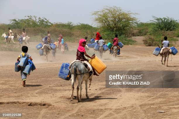 Children ride donkey's to fetch water in jerrycans at a makeshift camp for people who fled fighting between Huthi rebels and the Saudi-backed...