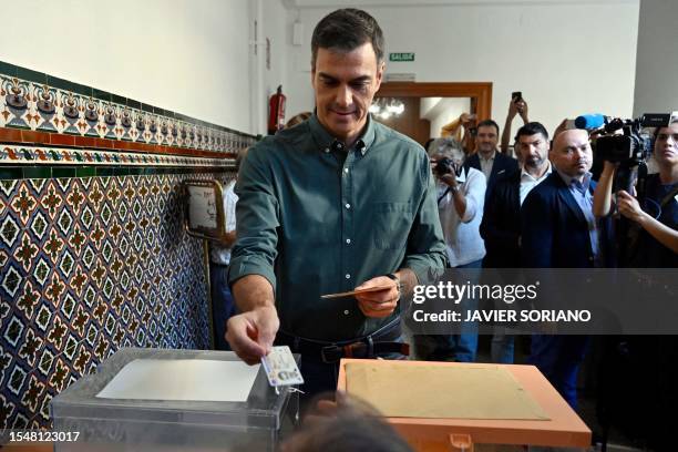 Spanish Prime Minister and Socialist Party candidate for re-election Pedro Sanchez hands his identity card to the president of the polling station...