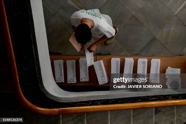 Man picks up ballots before voting at a polling station in Madrid, during Spain's general election on July 23, 2023. Spain votes today on whether to...