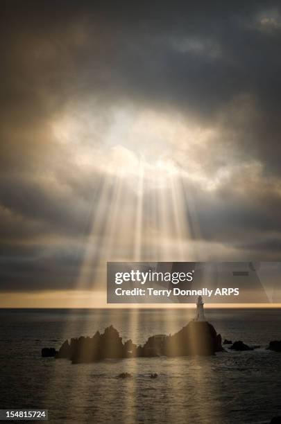 lighthouse under stormy sky with sundays - storm lighthouse stockfoto's en -beelden