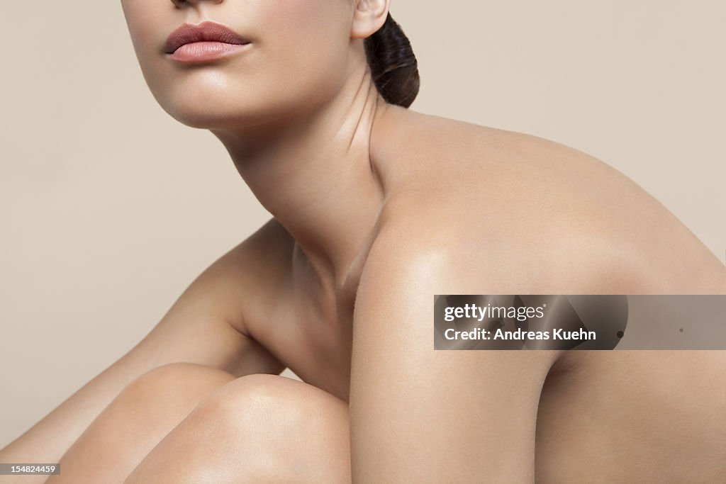 Seated nude young woman profile, cropped.