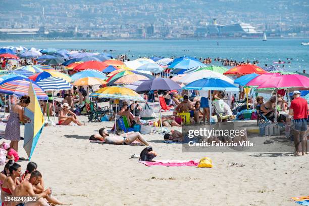 Lots of bathers under umbrellas at the 'playa', the city's sandy beach, to find refreshment on a scorching hot Sunday with a maximum alert level for...