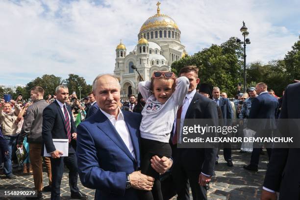Russia's President Vladimir Putin holds a child during his meeting with local residents in front of The Naval Cathedral of Saint Nicholas in...