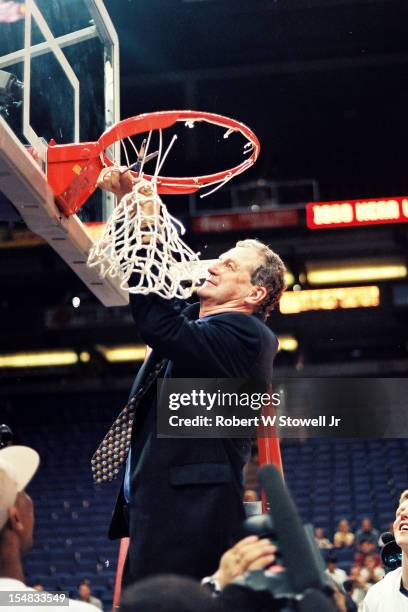 Italian-born American basketball coach Jim Calhoun, of the University of Connecticut, stands on a ladder and cuts down one of the nets in celebration...