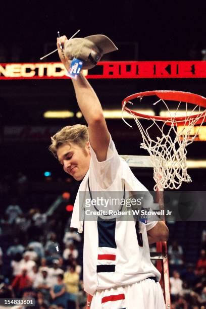 American basketball player Jake Voskuhl, of the University of Connecticut, stands on a ladder and waves a cap & piece of the net in celebration...