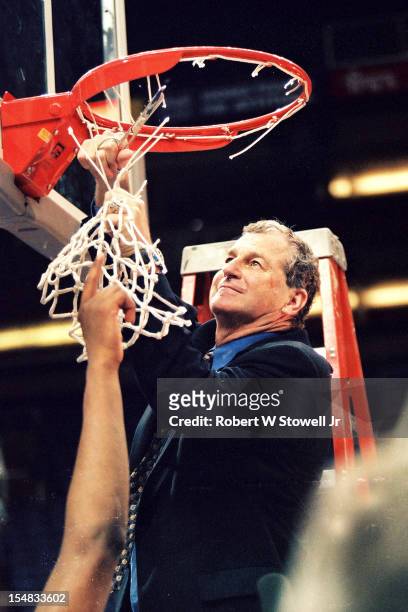 Italian-born American basketball coach Jim Calhoun, of the University of Connecticut, stands on a ladder and cuts down one of the nets in celebration...