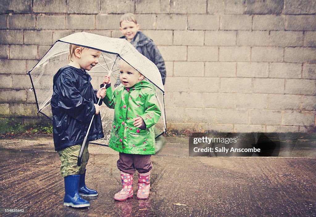 Two children sharing an umbrella in the rain