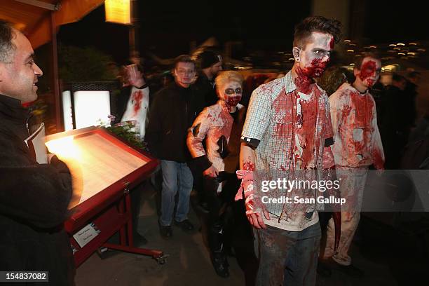 Zombie enthusiasts walk past an outdoor restaurant during a "Zombie Walk" in the city center on October 27, 2012 in Berlin, Germany. Approximately...