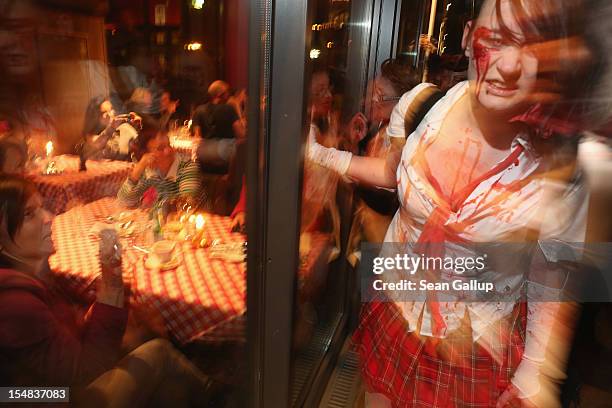 Diners in a restaurant look on as zombie enthusiasts walk by during a "Zombie Walk" in the city center on October 27, 2012 in Berlin, Germany....
