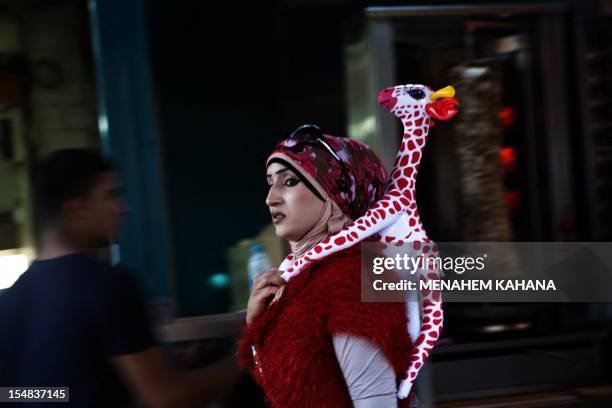 An Arab Israeli woman walks with an inflatable Giraffe in the street during a festival on the second day of Eid al-Adha holidays in the northern...