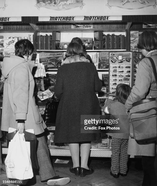 Shoppers browse a window display of toy cars in a shop window of Selfridges department store on Oxford Street in the West End of London, England,...