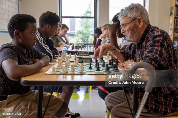 Congolese asylum seeker Valere, 10. And retired orthopedic surgeon Dr. Laurie Leonard play a game of tournament chess on July 15, 2023 in Portland,...