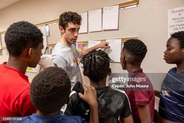 Chess coach Jacob Holden goes over matchups between young asylum seekers before a game of tournament chess on July 15, 2023 in Portland, Maine....