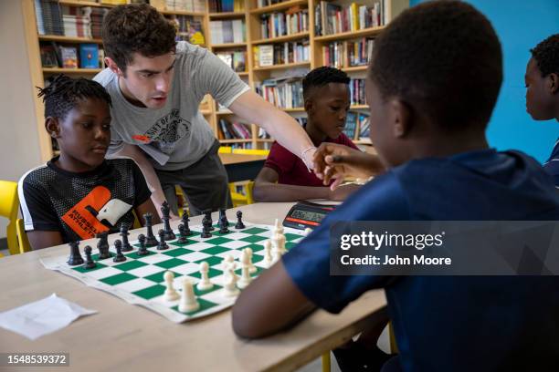 Chess coach Jacob Holden sets a timer for young asylum seekers before a game of tournament chess on July 15, 2023 in Portland, Maine. Holden left his...
