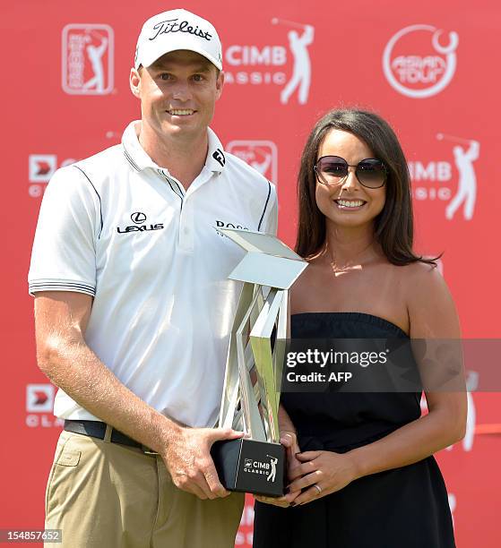 Nick Watney of the US and his wife Amber Watney pose with the trophy after winning the 6.1 million USD CIMB Classic golf tournament at The Mines...