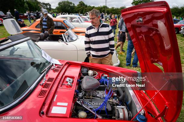 An enthusiast looks at the engine of a 1965 Sunbeam Tiger mk1 during the annual classic car and motorcycle show on July 16, 2023 in Dudswell, near...