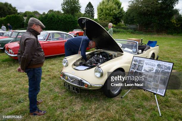 The owner polishes the 2.5 litre hemi-head V8 engine in a 1961 S.P. 250 Daimler during the annual classic car and motorcycle show on July 16, 2023 in...