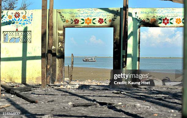 Boat sails in the distance past a detroyed mosque at quarter No.3 in Pauktaw township, that was burned in recent violence between Buddhist Rakhine...