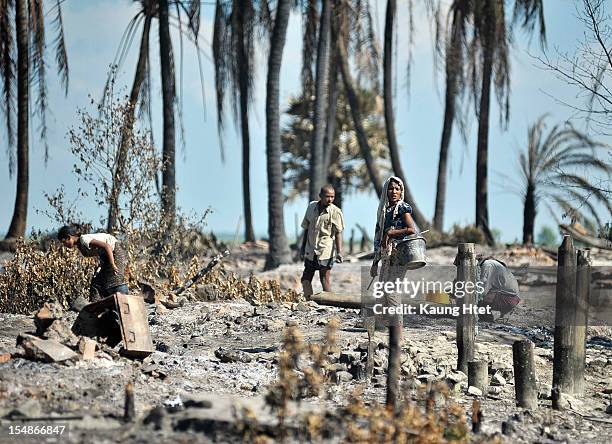 People look for pieces of metal in the rubble of quarter No.3 in Pauktaw township, that was burned in recent violence between Buddhist Rakhine and...