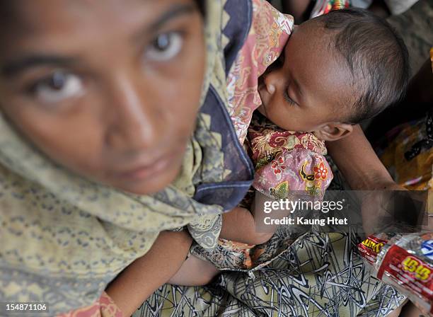 Displaced people sit together after arriving to Thae chaung refugee camp October 28, 2012 in Sittwe, Myanmar. Over twenty thousand people have been...