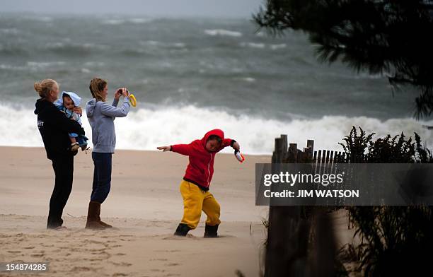 Elizabeth Row holds her son Teddy as her daughter Thomasina takes pictures and her other son Matthew plays as tidal surge from Hurricane Sandy comes...