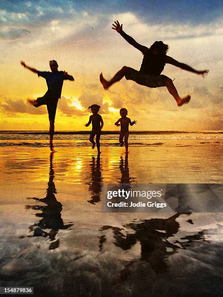 family running and jumping at beach sunset - kuta stock-fotos und bilder