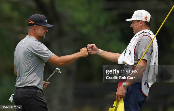 Ryan Moore of the United States reacts to his birdie putt with his caddie on the fifth green during the final round of the Barbasol Championship at...