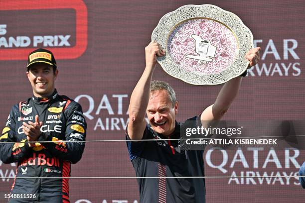 Third placed Red Bull Racing's Mexican driver Sergio Perez applauds as Red Bull Racing's chief engineer Paul Monaghan lifts their Team-Winner trophy...