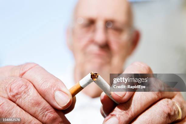 nie zu spät, um das rauchen: alter mann bricht zigarette - quit smoking stock-fotos und bilder