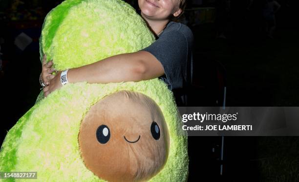 An attendee hugs a giant stuffed avocado that they won on opening day at the Burlington County Farm Fair in Columbus, New Jersey, on July 18, 2023.