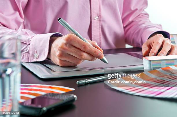 close-up of graphic designer working on digital tablet, colour swatches - grafisch ontwerpbureau stockfoto's en -beelden