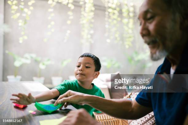 asian grandfather making origami together with his grandson at home. - origami instructions stock pictures, royalty-free photos & images