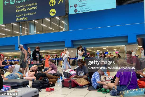 Tourists wait in the airport's departure hall as evacuations are underway due to wildfires, on the Greek island of Rhodes on July 23, 2023. Locals...