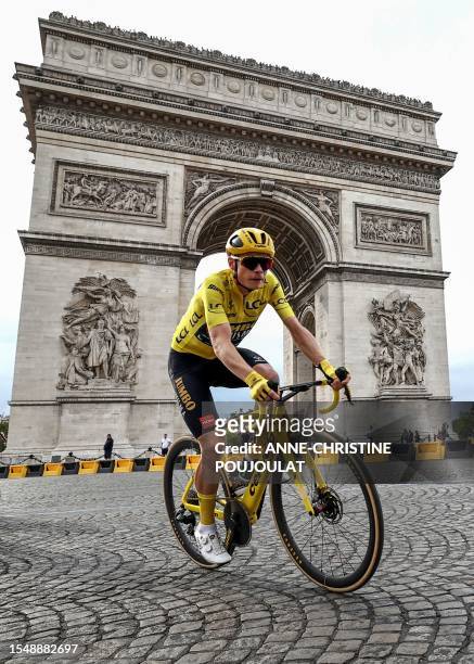 Jumbo-Visma's Danish rider Jonas Vingegaard wearing the overall leader's yellow jersey cycles past the Arc de Triomphe on Place de l'Etoile during...