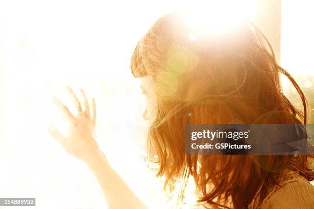 rotes haar-frau von hinten angestrahltes von sonne mit hand am fenster - hands sun stock-fotos und bilder