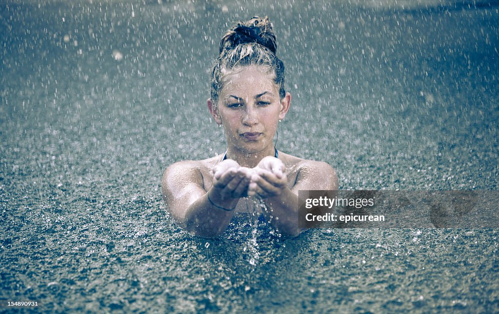 Young beautiful woman swimming in the rain