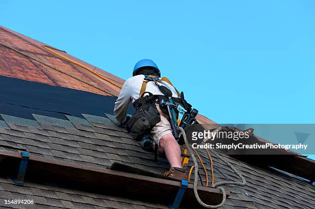 construction worker doing work on a rooftop - safety harness stockfoto's en -beelden