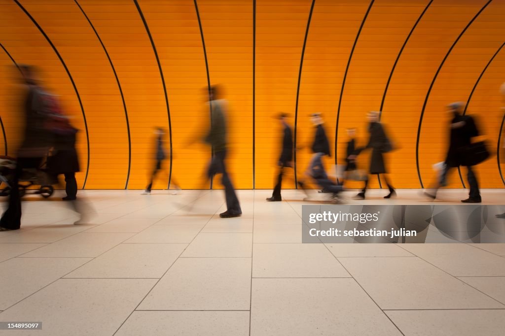 Große Gruppe von Menschen vor modernen orange U-Bahn-Röhre