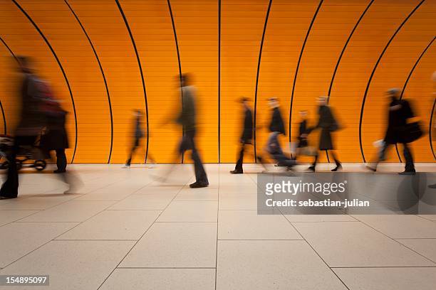 large group of people against modern orange subway tube - railwaystation stockfoto's en -beelden