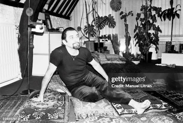 Maurice BEJART sitting on cushions in his apartment in Brussels, Around his neck, he wears a mini-Koran has suspended a thin gold chain.