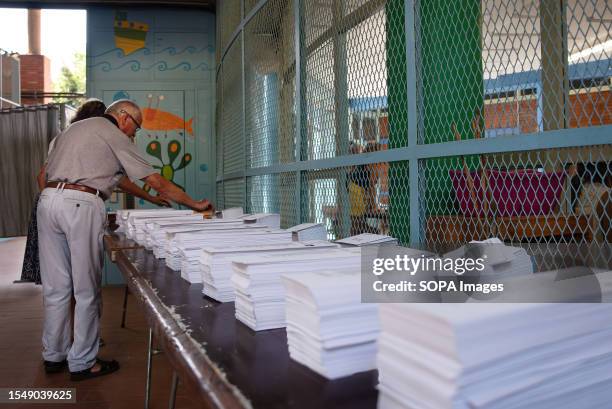An elderly couple collect ballots at the entrance to the Escola Mercè Rodoreda during the 2023 Spanish general election.