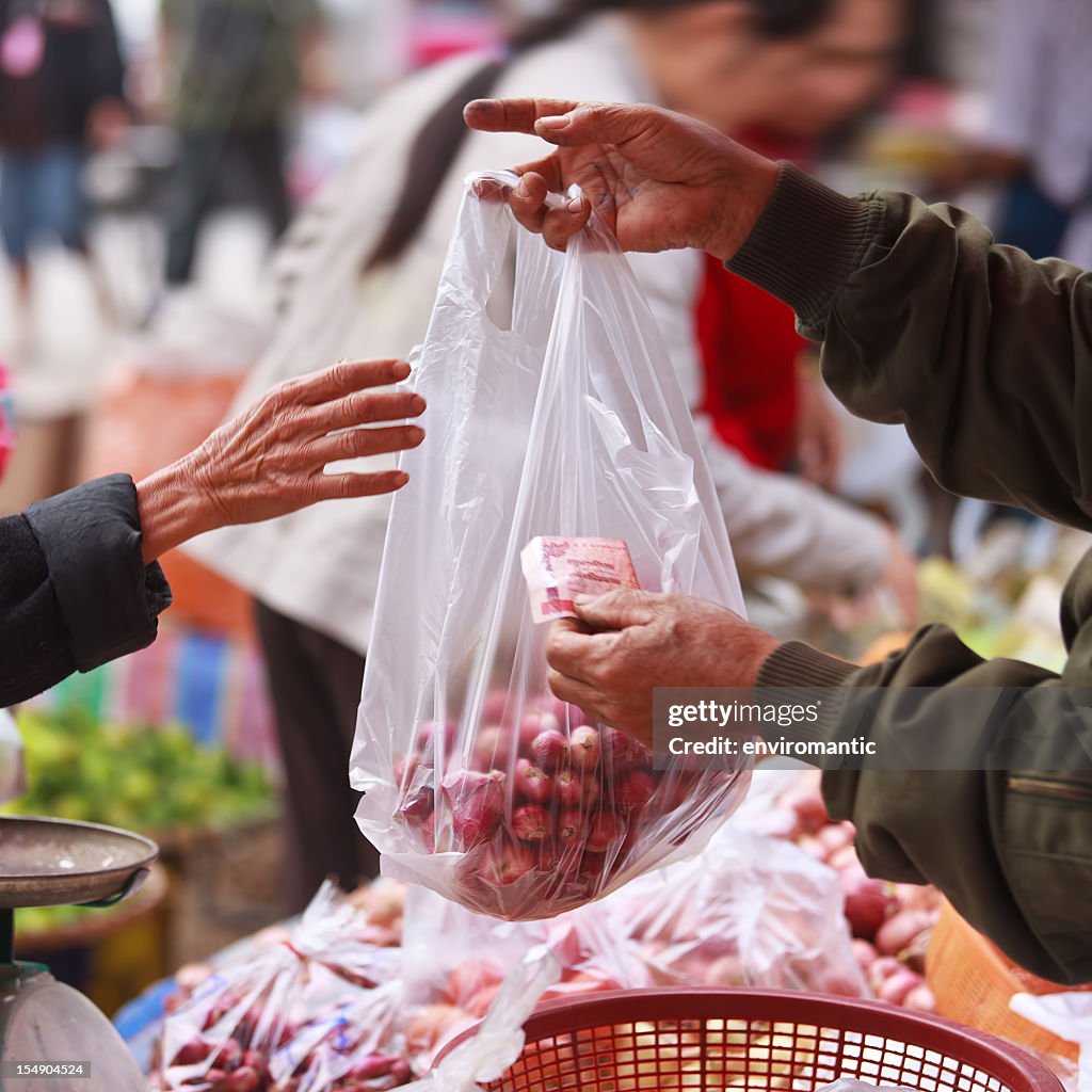 Exchanging money for vegetables in a Thai market.