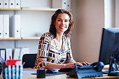 Smiling businesswoman at office desk with a computer
