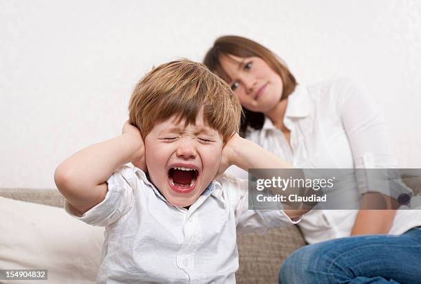 crying boy is covering his ears - children shouting stock pictures, royalty-free photos & images