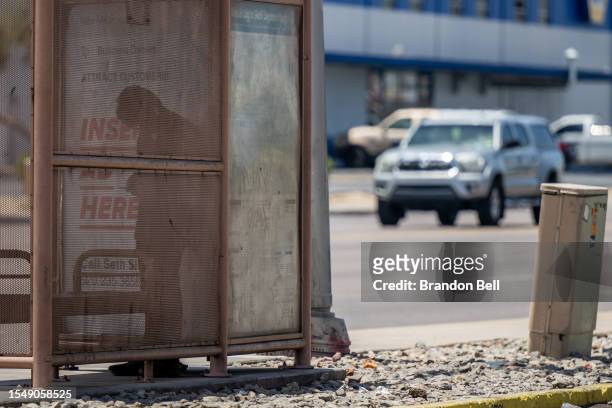 Person takes shelter at a bus stop from blistering heat that was forecast to reach 115 degrees Fahrenheit on July 16, 2023 in Phoenix, Arizona. A...