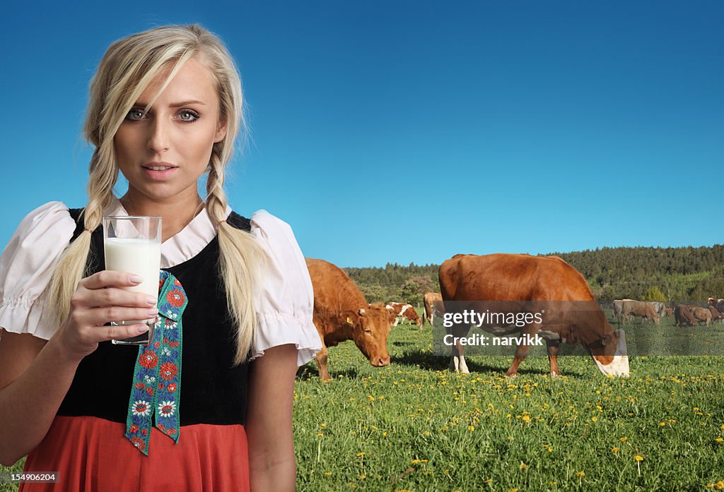 Fille de la campagne avec verre de lait et les vaches derrière