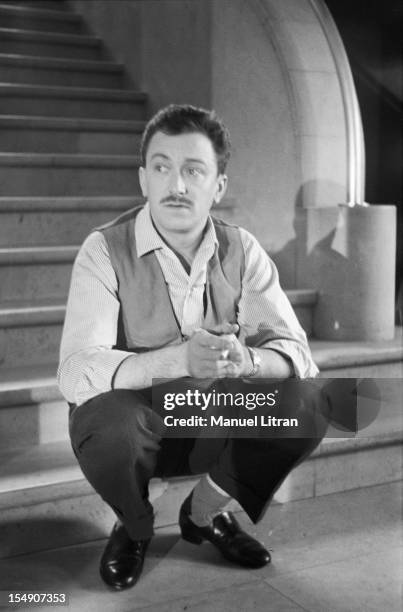 Robert Dhery sitting on the steps of a staircase .